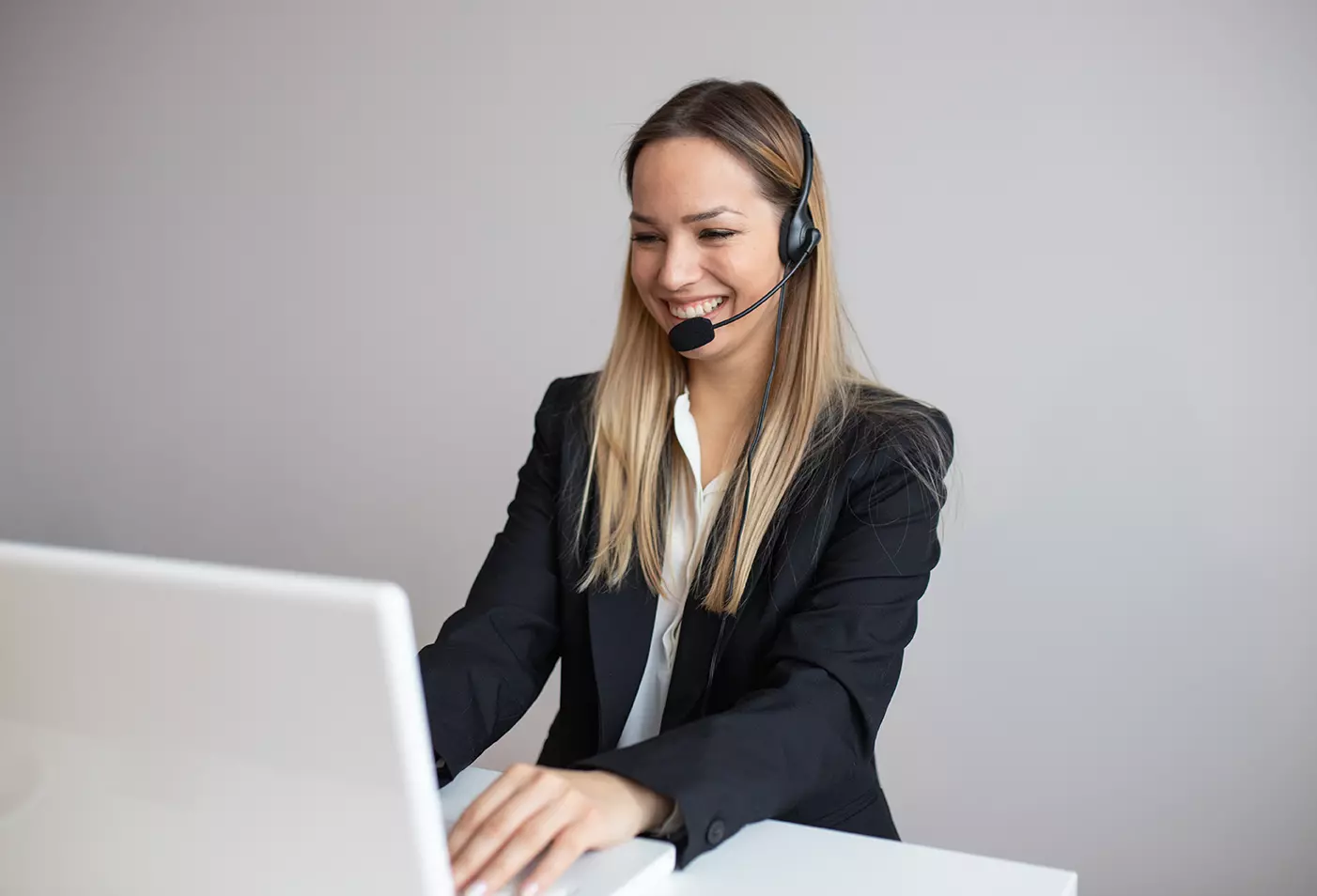 Mujer ejecutiva de atención con diadema y micrófono frente a computadora y las claves de escalar tickets en un Help Desk