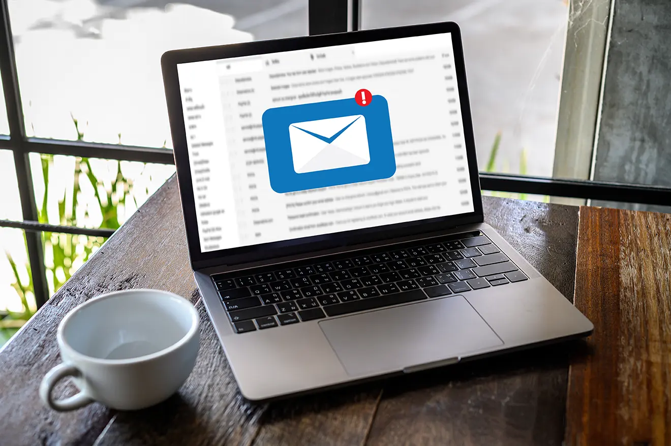 Computadora sobre escritorio en la pantalla la bandeja de correo electrónico mostrando como Gmail ahora permite adjuntar correos electrónicos.