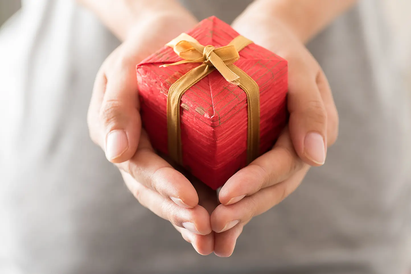Persona con un pequeño regalo entre sus manos para tener una Navidad con sentido.
