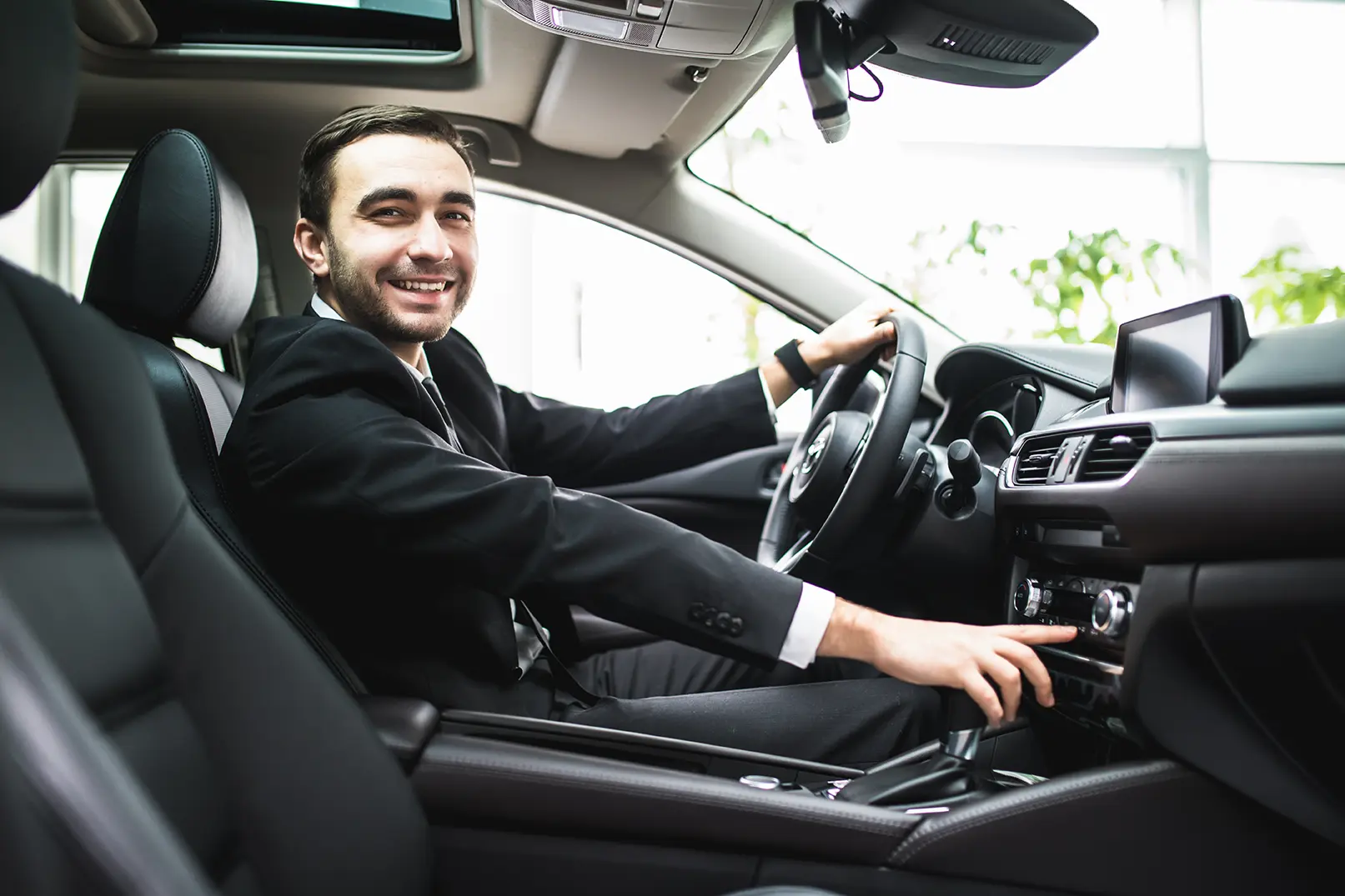 Conductor de Uber en su auto sonriendo a la cámara. Ususarios de Uber pueden determinar a sus conductores favoritos.