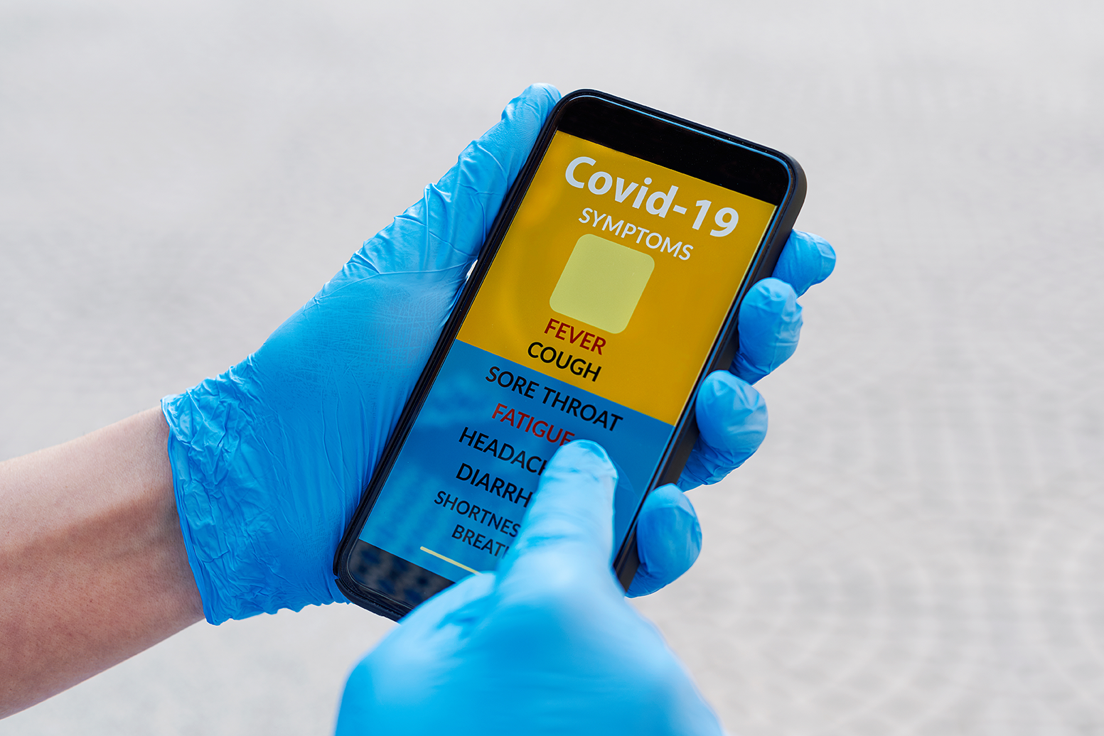 Persona manipulando un celular con guantes de látex en la aplicación sobre coronavirus descargando un ransomware en el teléfono
