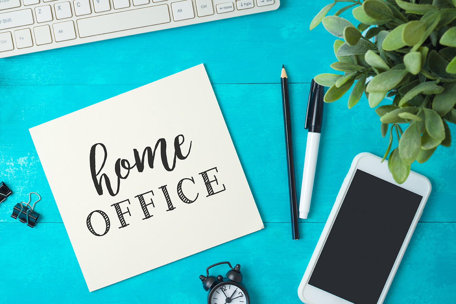 Teclado de computadora, celular, plumas y una nota de home office sobre escritorio y 5 consejos para incrementar la productividad en home office