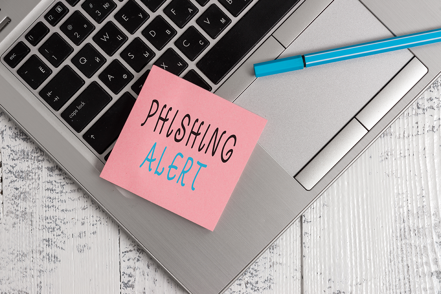 Computadora sobre escritorio con una nota de phishing alert sobre el teclado así como Apple ha sido la marca más imitada en el 2020 para hacer ataques de phishing.