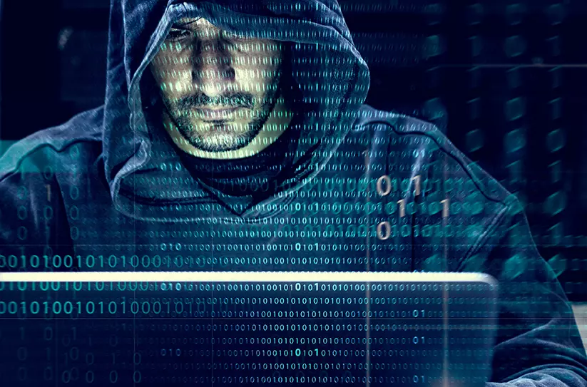 Hombre con sudadera con capucha frente a una computadora representando el ciberataque masivo a twitter que fue perpetrado por un grupo de adolescentes