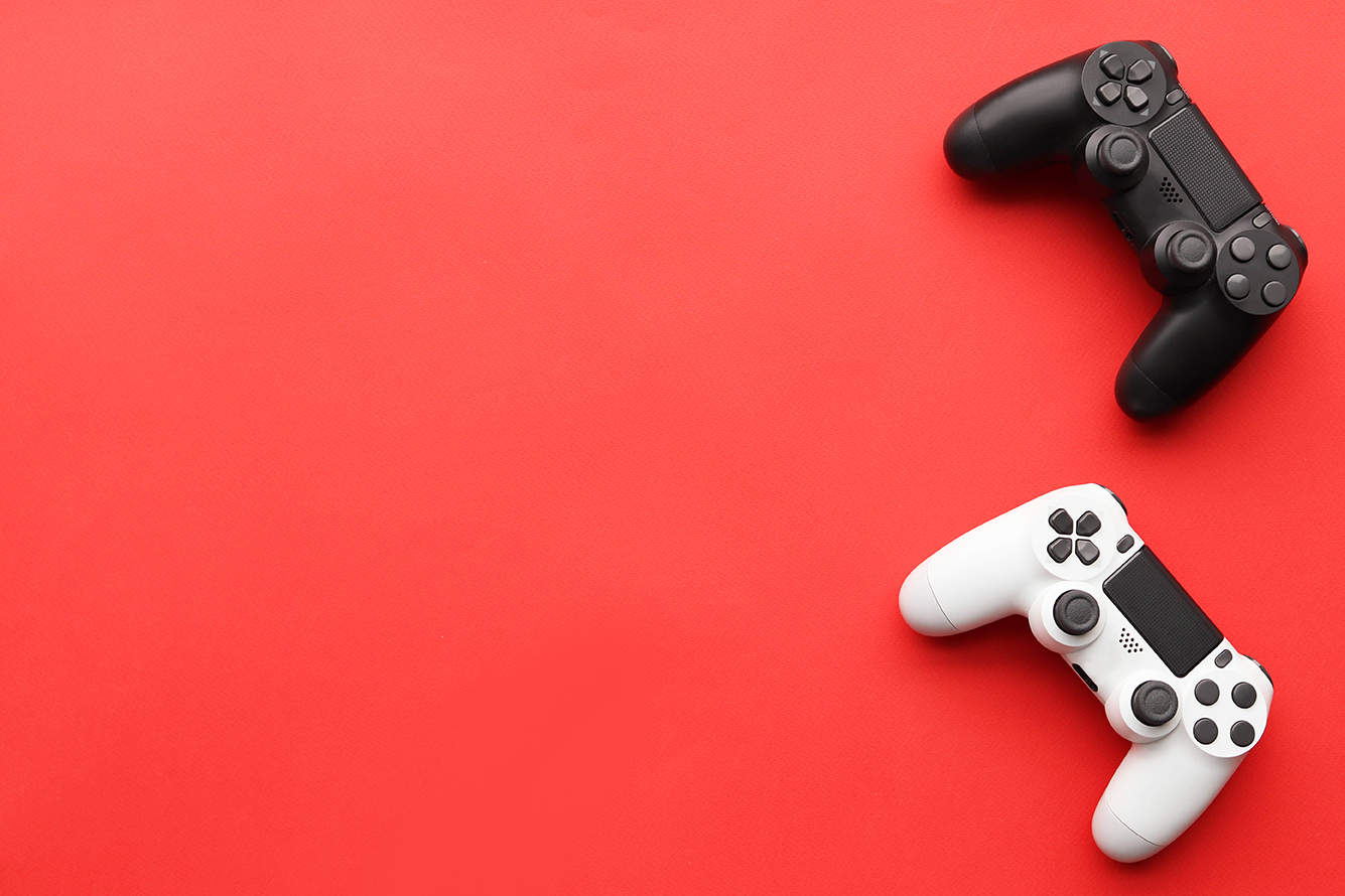 Fondo color rojo y dos controles de videojuegos uno color blanco y otro color negro. Nintendo confirma ciberataque en cuentas de sus usuarios