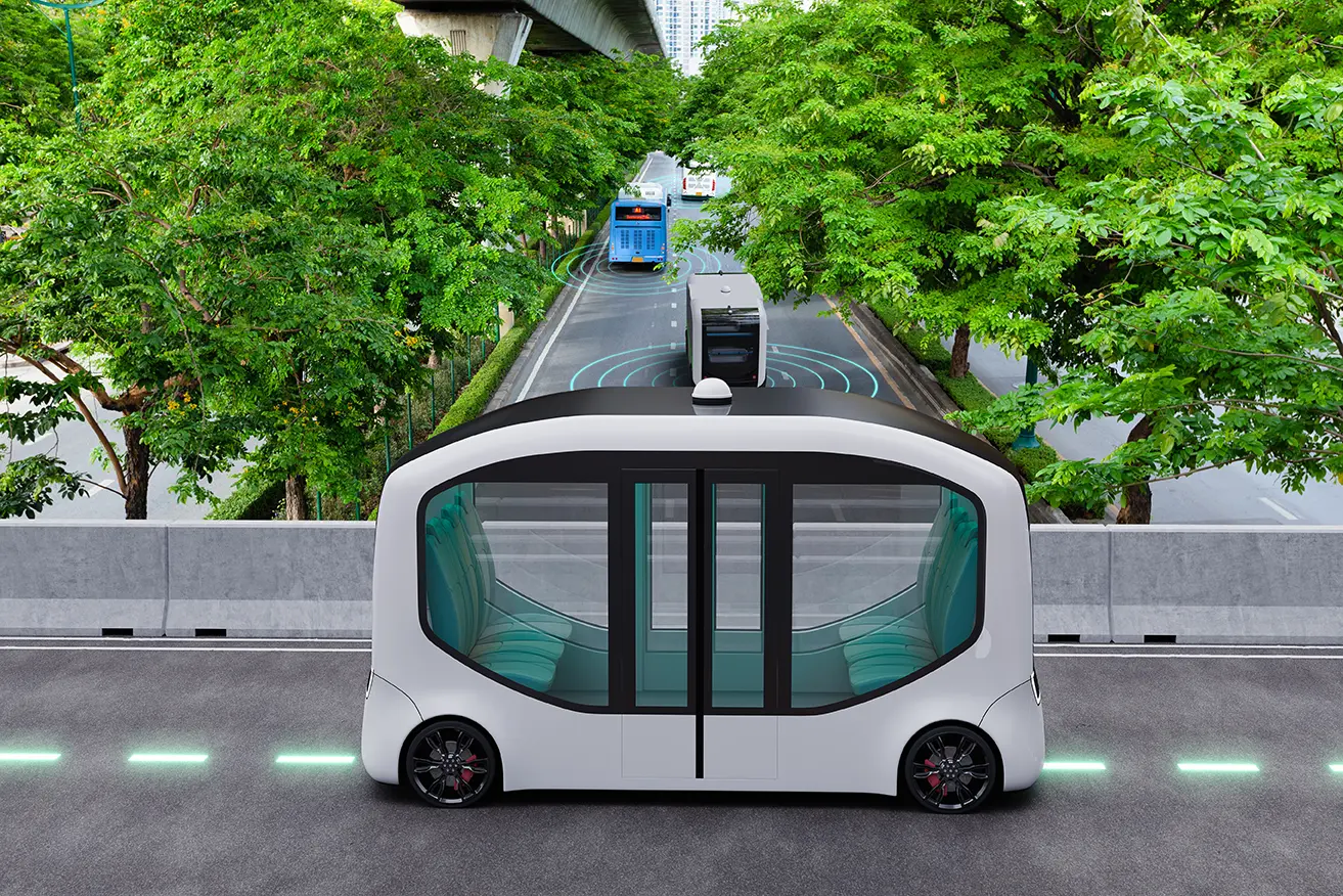 Tipo autobús color blanco estacionado sobre una calle con árboles de fondo representando al robot que está patrullando calles de Singapur para verificar distanciamiento social.