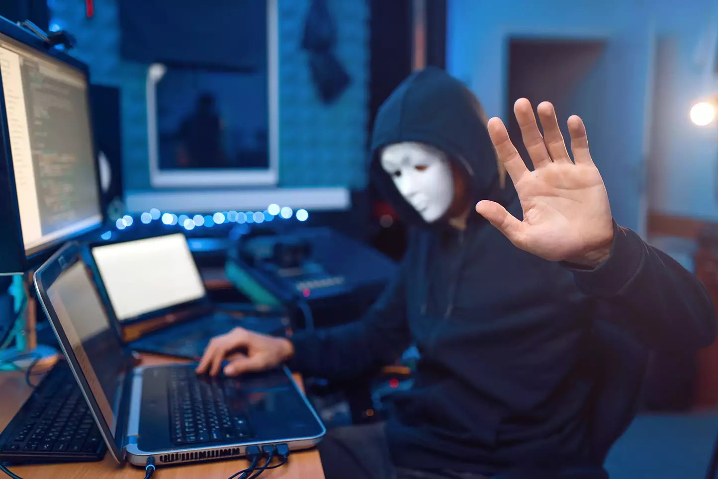 hacker con máscara y mano abierta usando información vulnerable por usar Softwares desactualizados