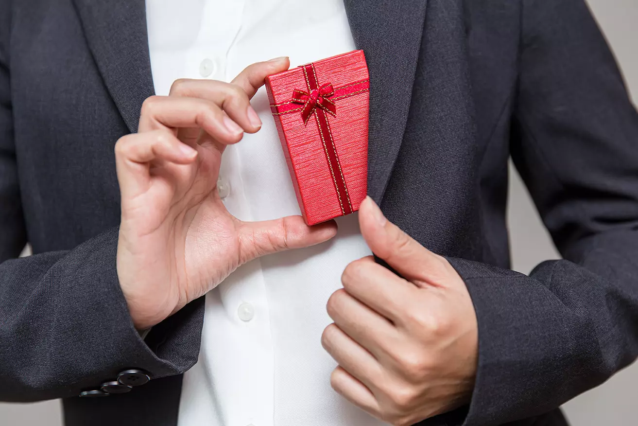 Hombre sacando caja de regalo rojo de su traje
