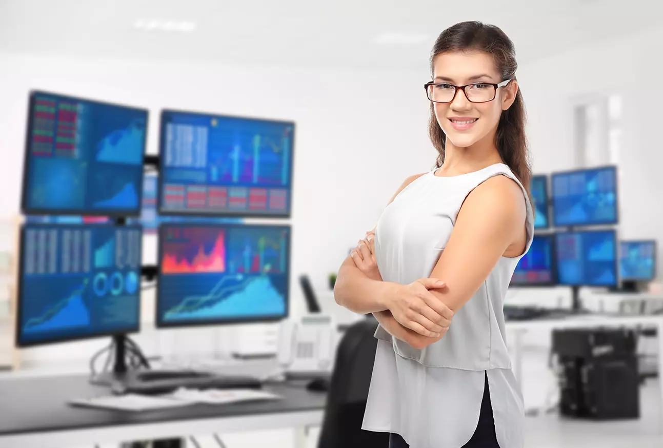 Mujer frente a escritorio con varias computadoras, representando las 5 formas de mejorar la entrega del servicio de la gestión de activos de TI.