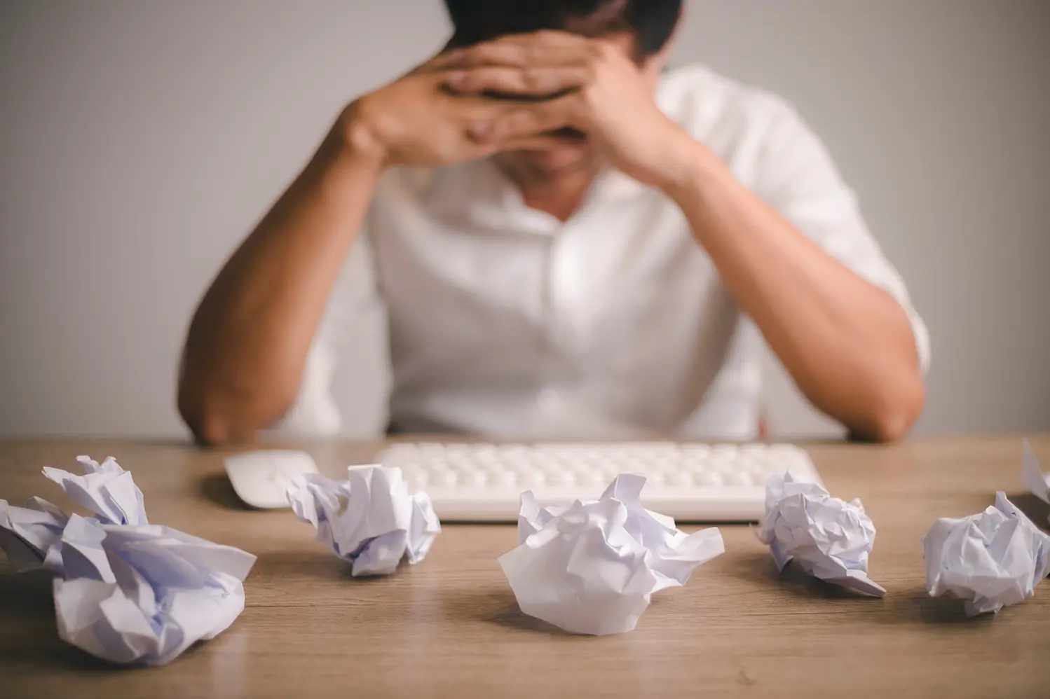 Hombre sentado en su escritorio con muchas hojas de papel alrededor sin poder concentrarse, representando 8 cosas que afectan la productividad en la gestión de TI.
