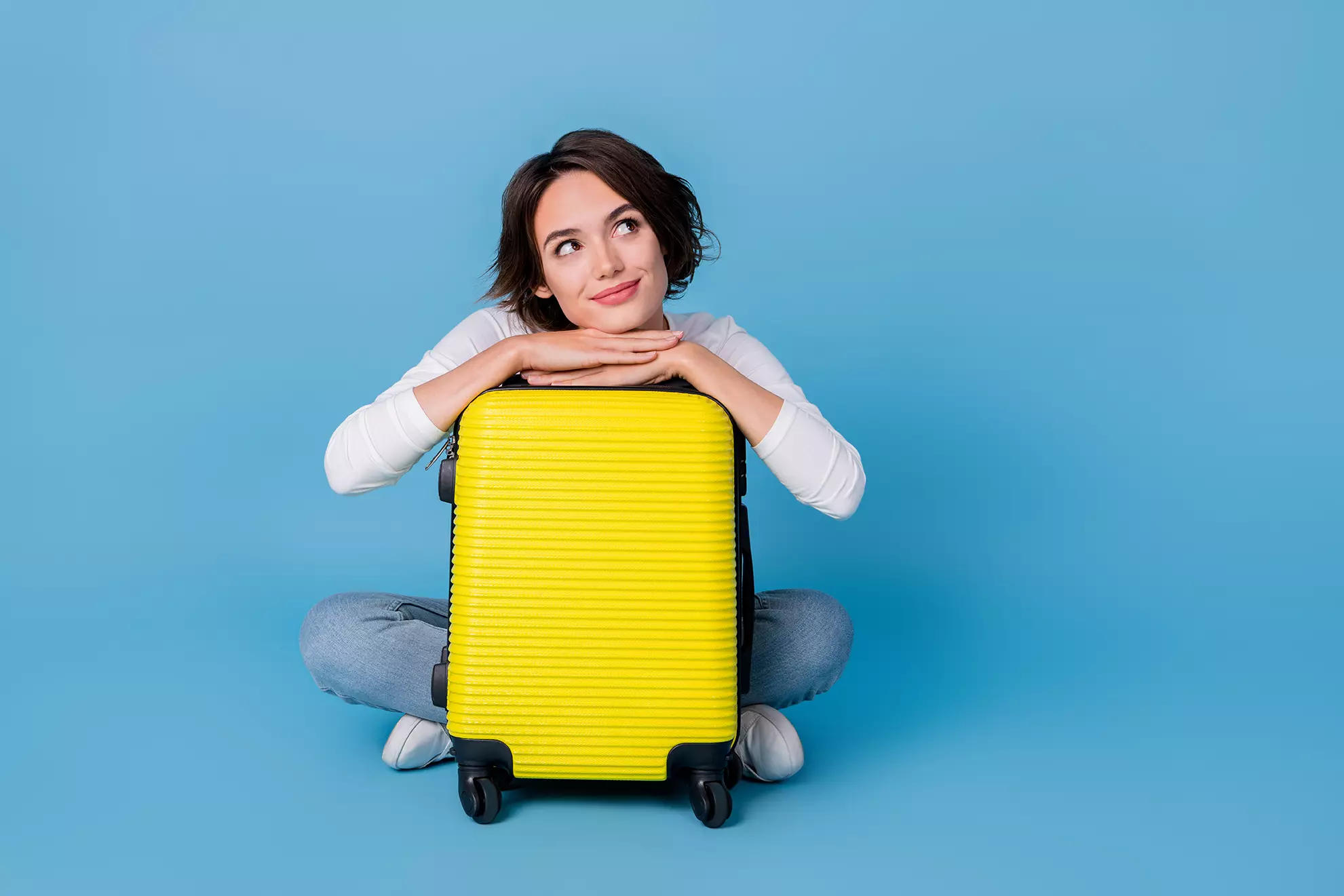 Mujer recargada en una maleta representando que Airbnb hará shows de tv para convencer a la gente de viajar mas
