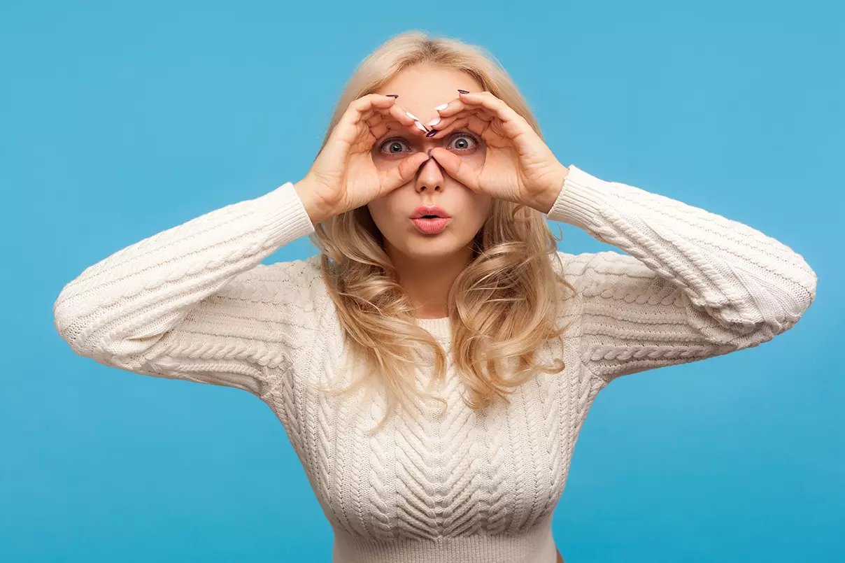 Mujer simulando con sus manos visores sobre los ojos representando asumir el rol de observador consciente.