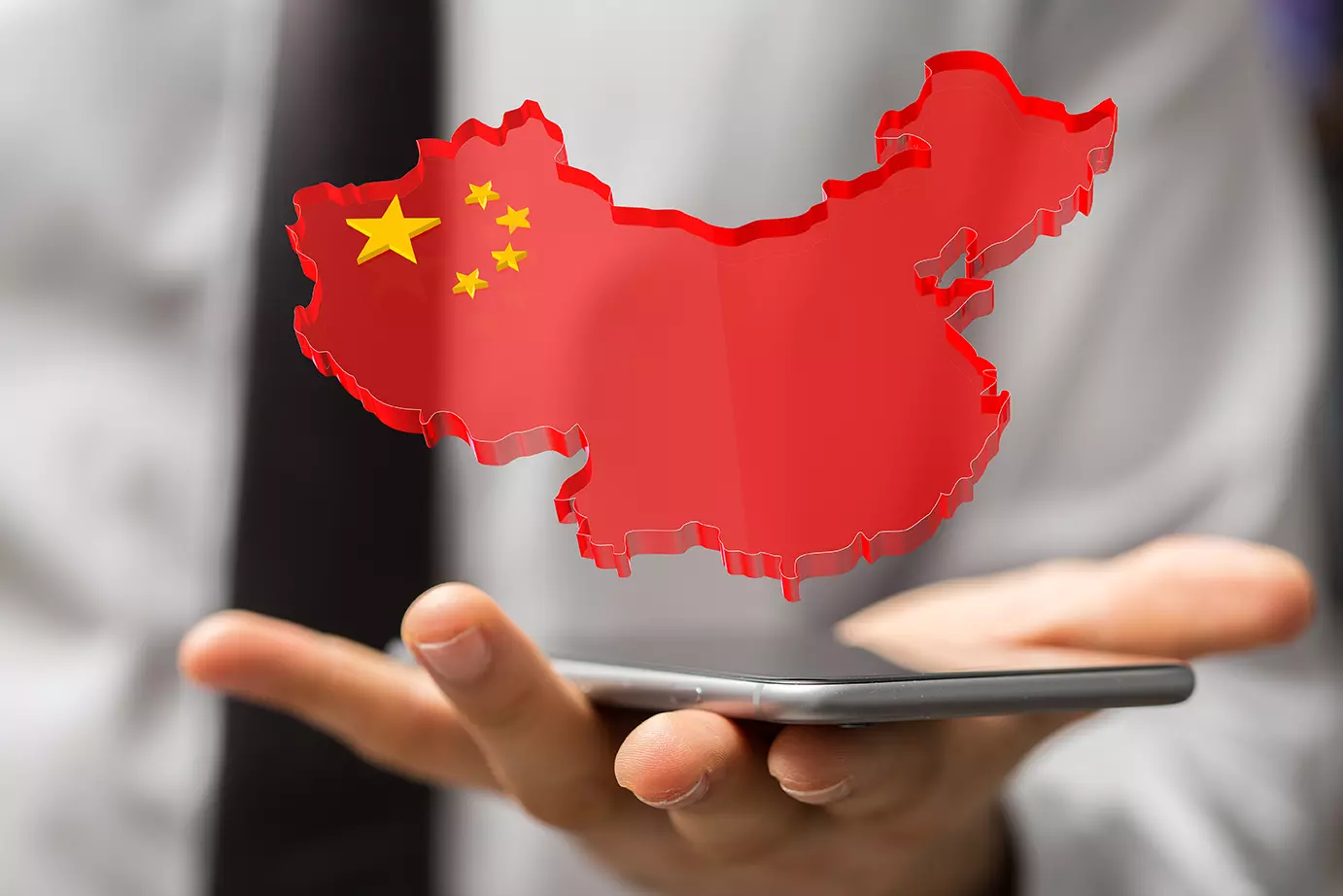 Hombre sosteniendo un celular y el país de China sobre él de forma digital, representando como China sería el país que mas gastará en Inteligencia Artificial este año.
