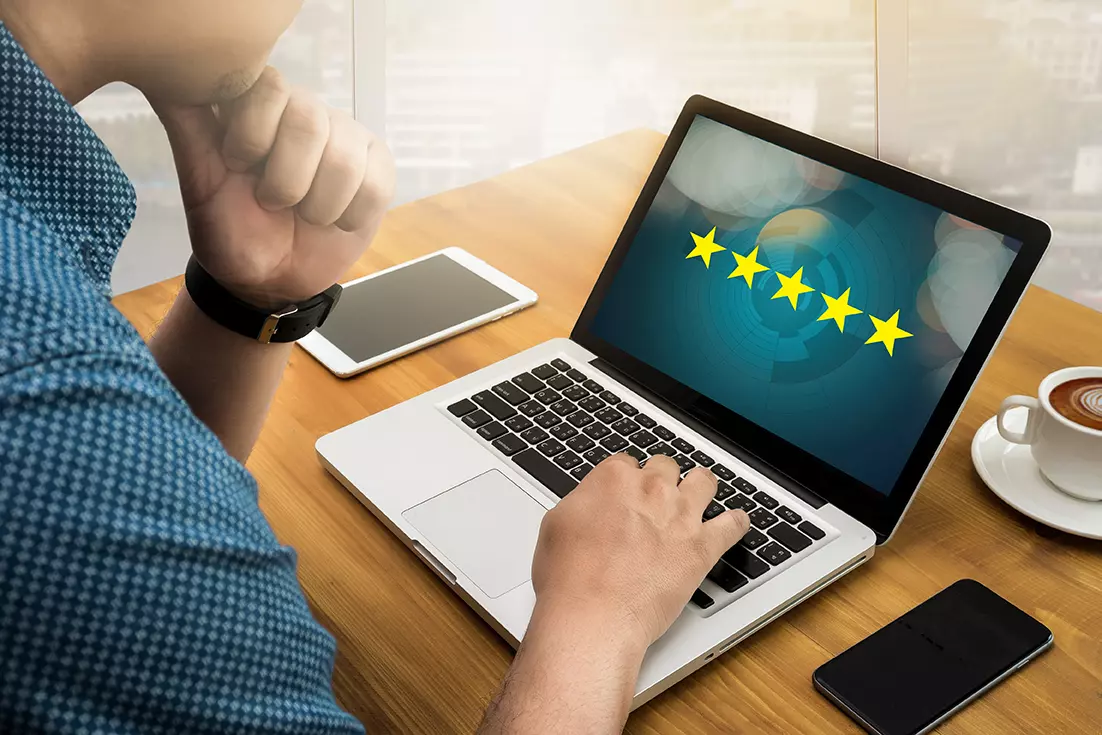 Hombre frente a computadora en la pantalla con 5 estrellas mostrando cómo TI afecta la estrategia de experiencia del cliente.