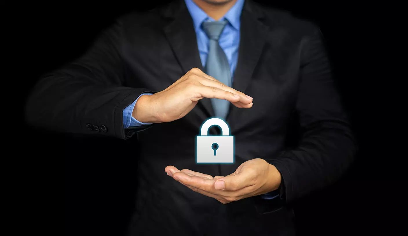Hombre con traje sosteniendo entre sus manos un candado de seguridad mostrando cómo construir confianza en la ciberseguridad entre los empleados