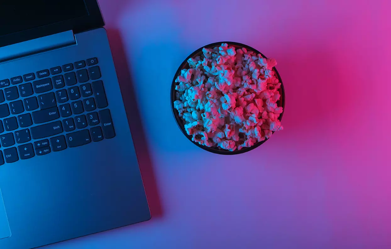 Un tazón de palomitas a lado de una laptop