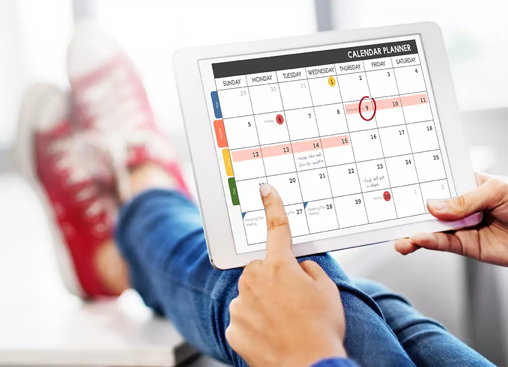 Persona revisando calendario en su tablet llevando el control de Actividades 101: Descubriendo la ciencia del orden.