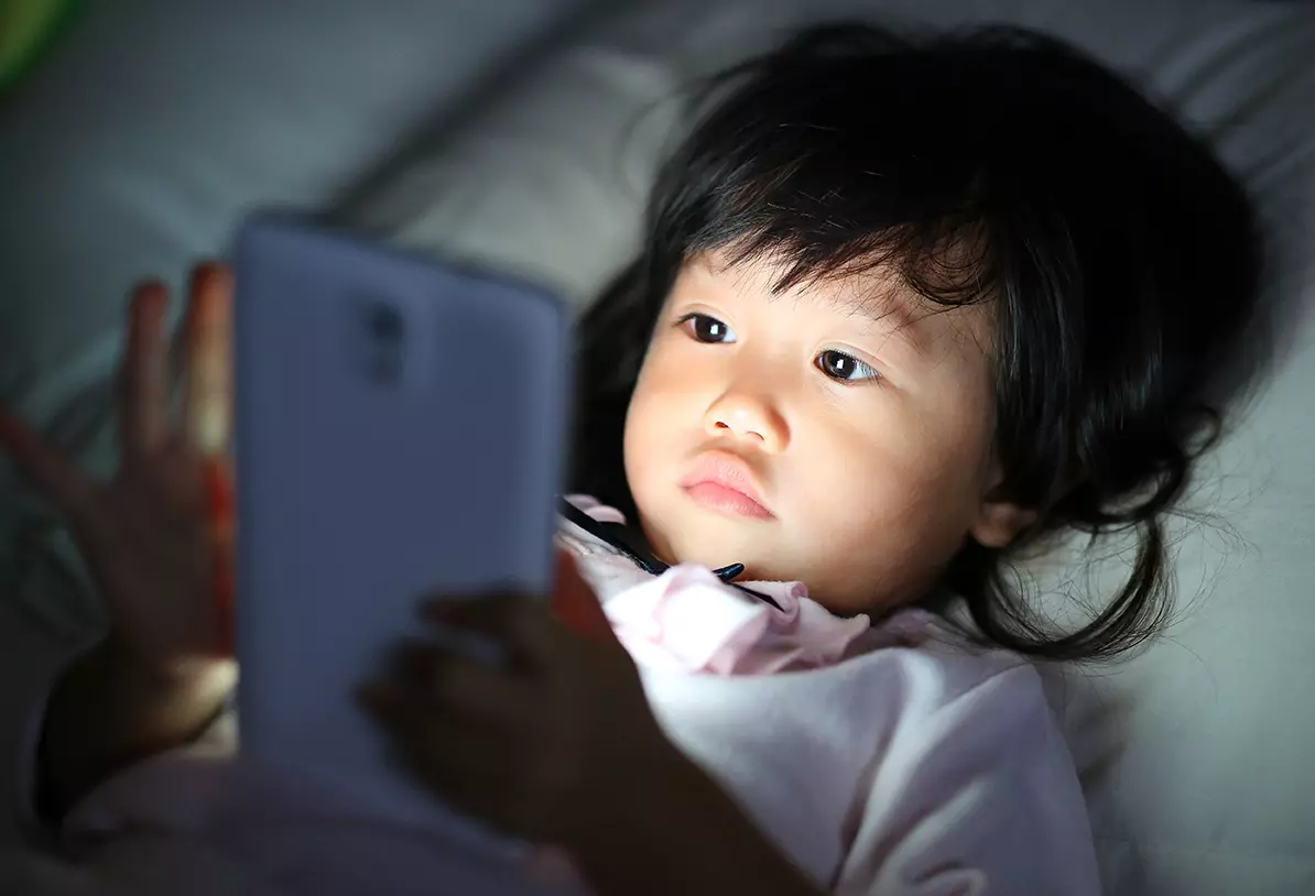Niño japonés viendo un celular representando como el gobierno de Japón cree que los teléfonos inteligentes están deteriorando la vista de los niños