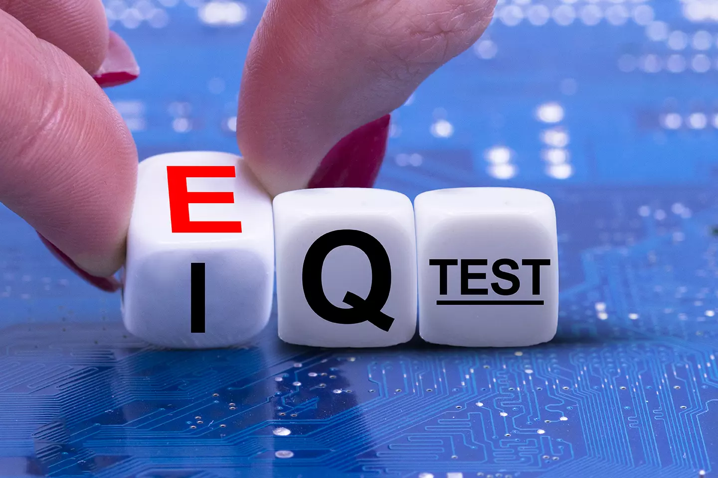 Persona tomando unos dados entre sus manos con las letras IQ test, representando Emociones inteligentes y la inteligencia emocional en el ámbito laboral.