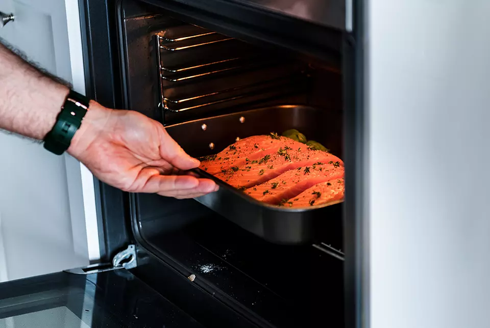 Persona metiendo comida al horno mostrando que GE lanza nuevo kit inteligente para hornear.