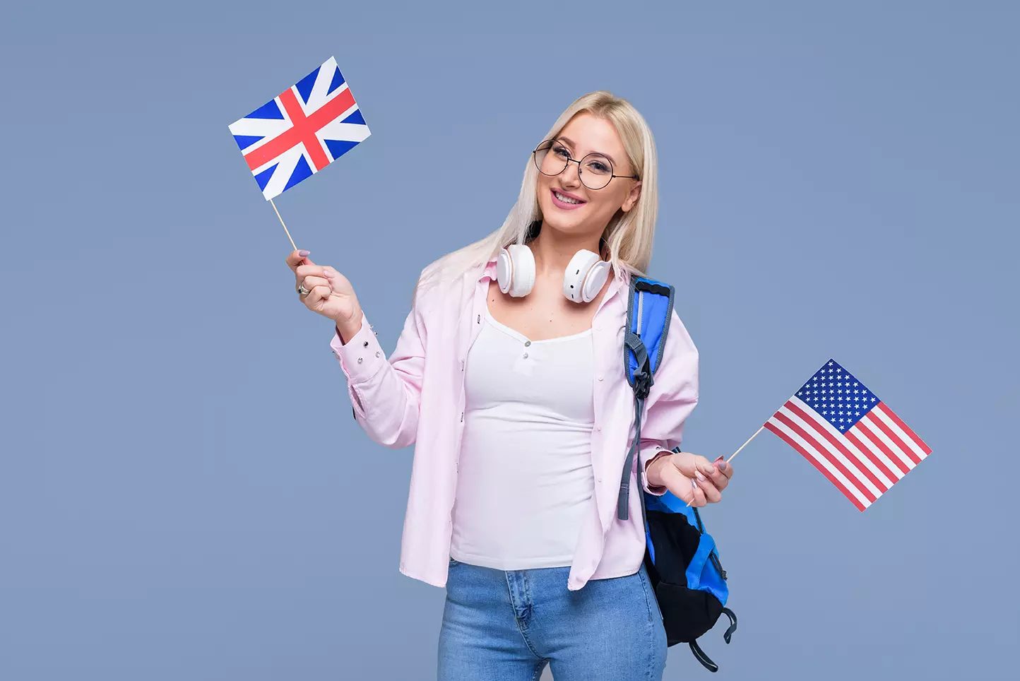 Mujer con mochila sosteniendo banderas de EUA y London mostrando la importancia del dominio del inglés en la búsqueda de empleo de TI.