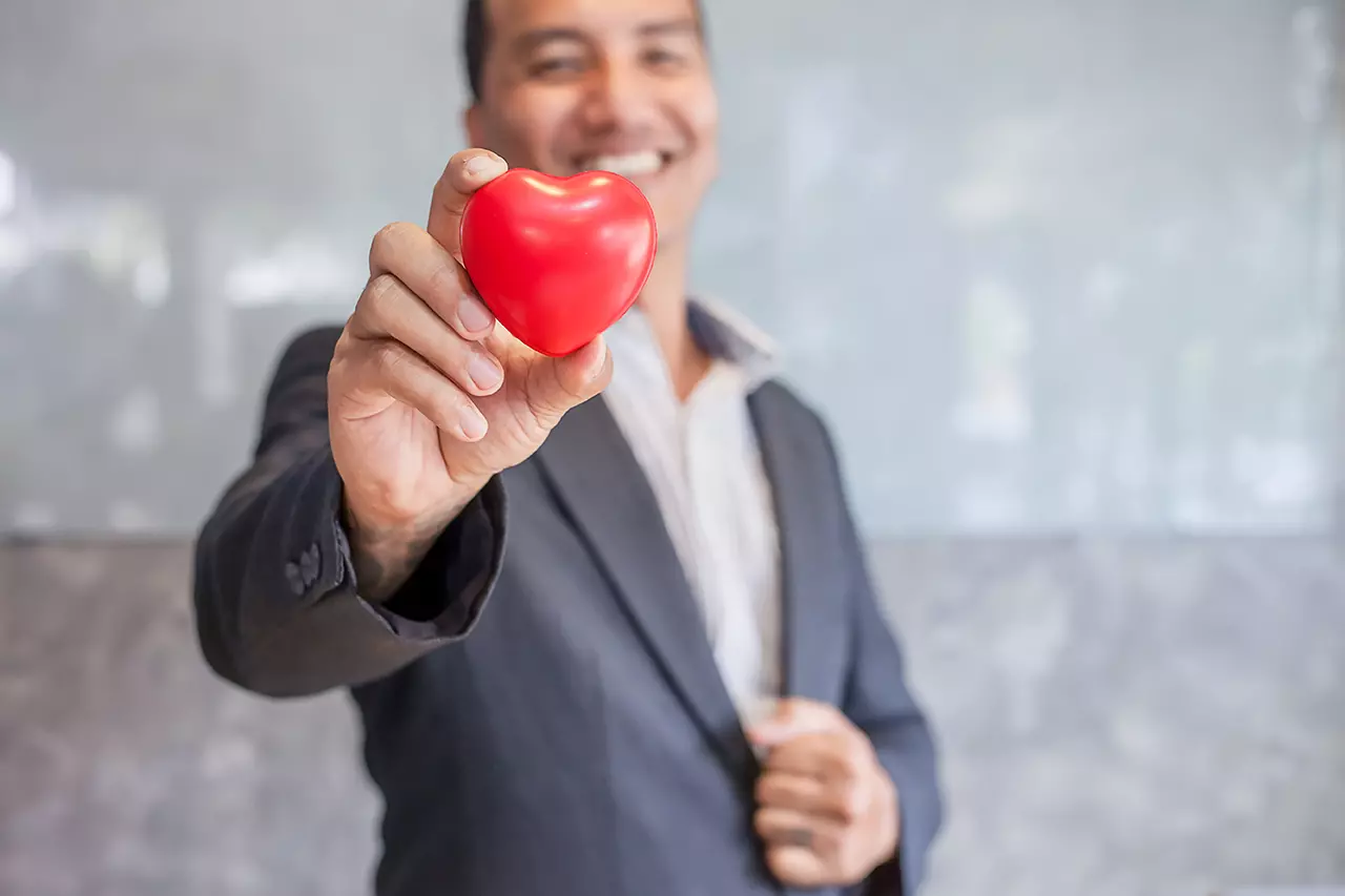 Hombre mostrando un corazón representando la importancia del salario emocional en el reclutamiento de perfiles de TI.