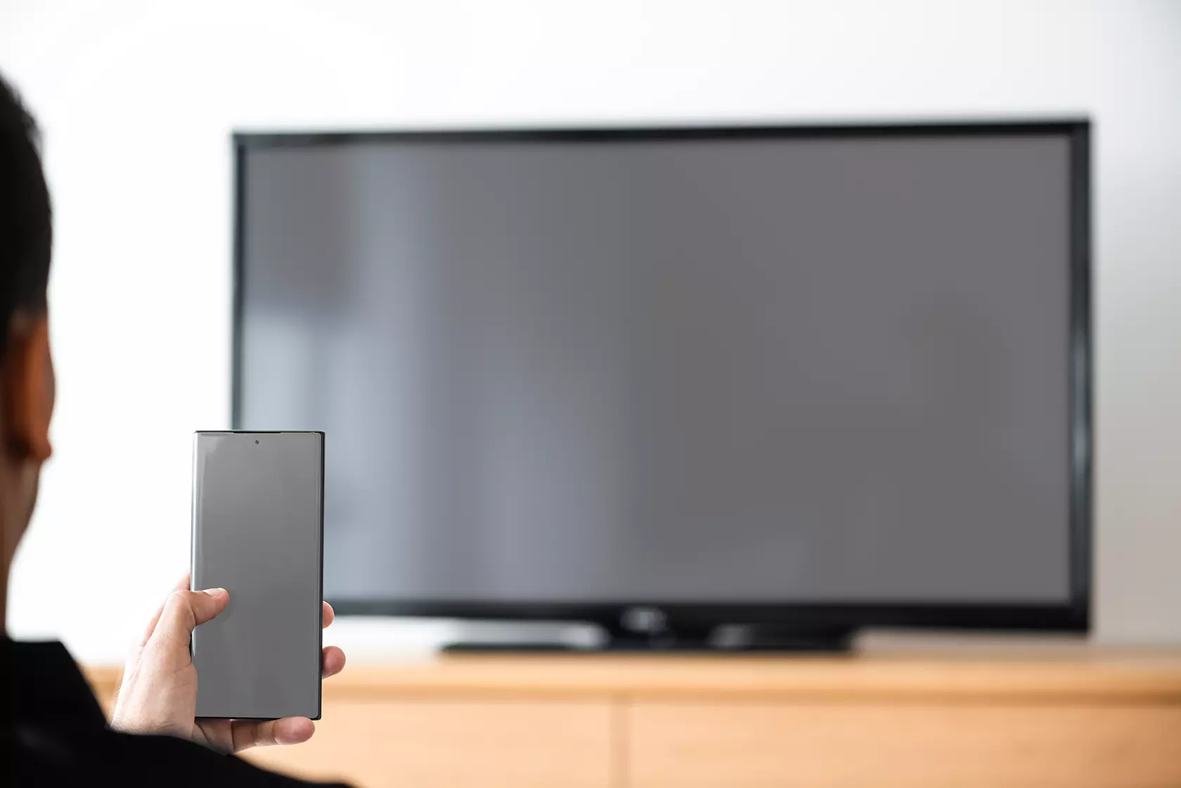 Persona con su celular conectando con pantalla, mostrando que la televisión plegable de LG saldrá al mercado en 2019.