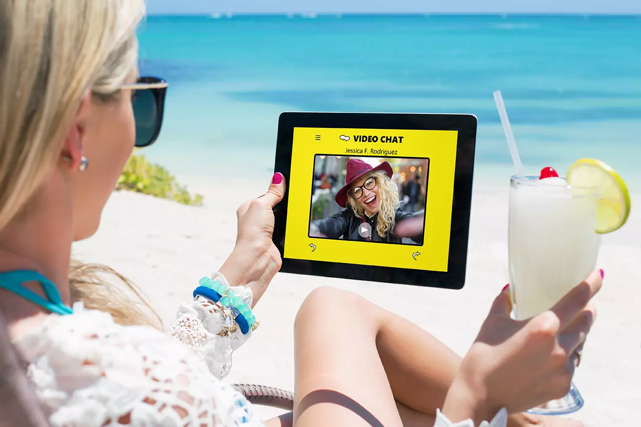 Mujer en la playa revisando snapchat en su tablet representando que Snapchat quiere lanzar shows de televisión.