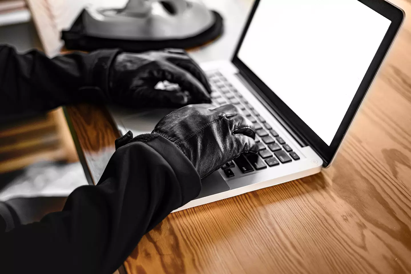 Hacker con guantes negros frente a computadora representando que Twitter, Paypal, Netflix, Amazon y Spotify sufren el ciberataque más grande de la década