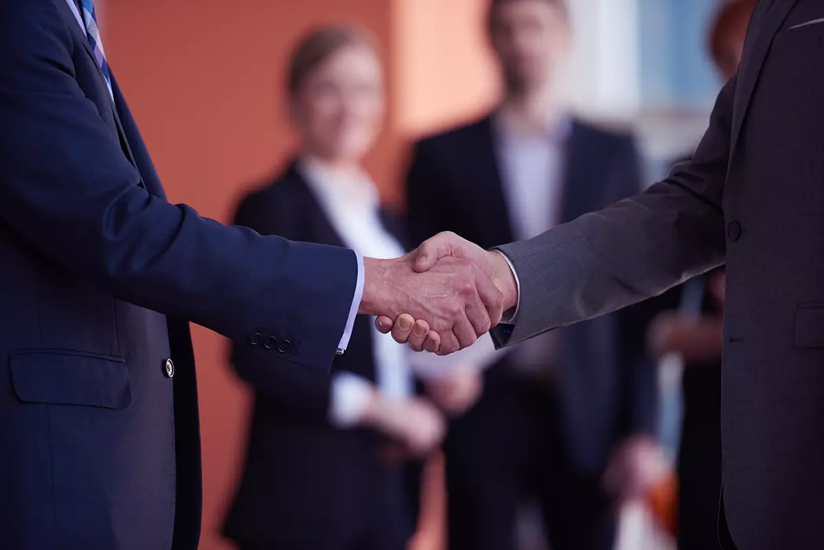 Socios dándose la mano cerrando un trato representando por qué elegir Partners en vez de proveedores