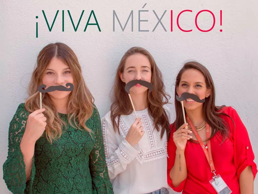 Tres mujeres mexicanas con colores verde, blanco y rojo con el letrero de ¡Viva México!, representando el orgullo mexicano en el extranjero