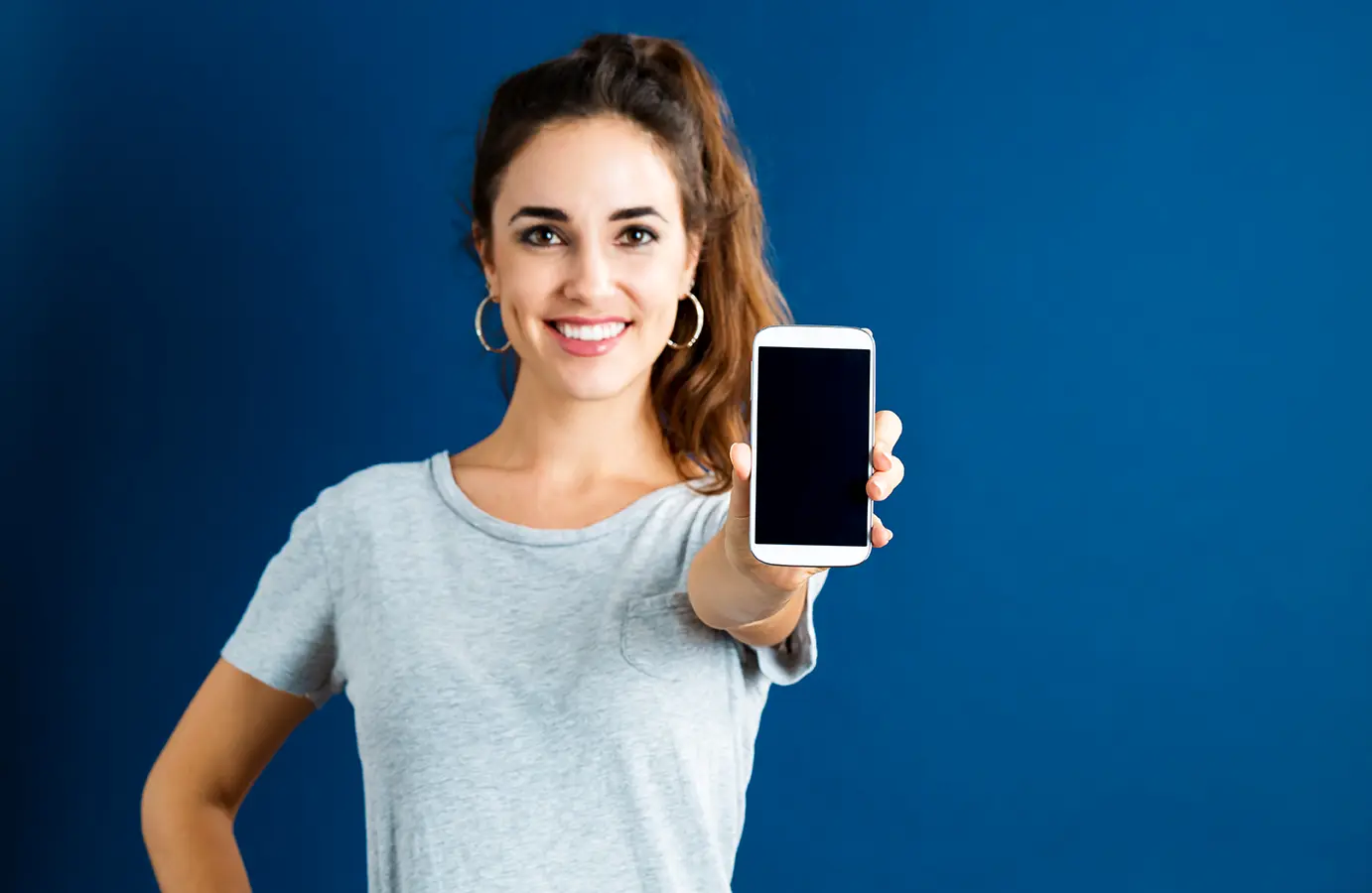 Mujer sosteniendo un iphone con fondo azul