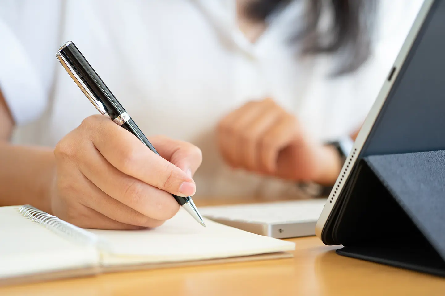Persona escribiendo en una hoja frente a una computadora, anotando 5 puntos básicos para crear un SLA funcional 5 puntos básicos.