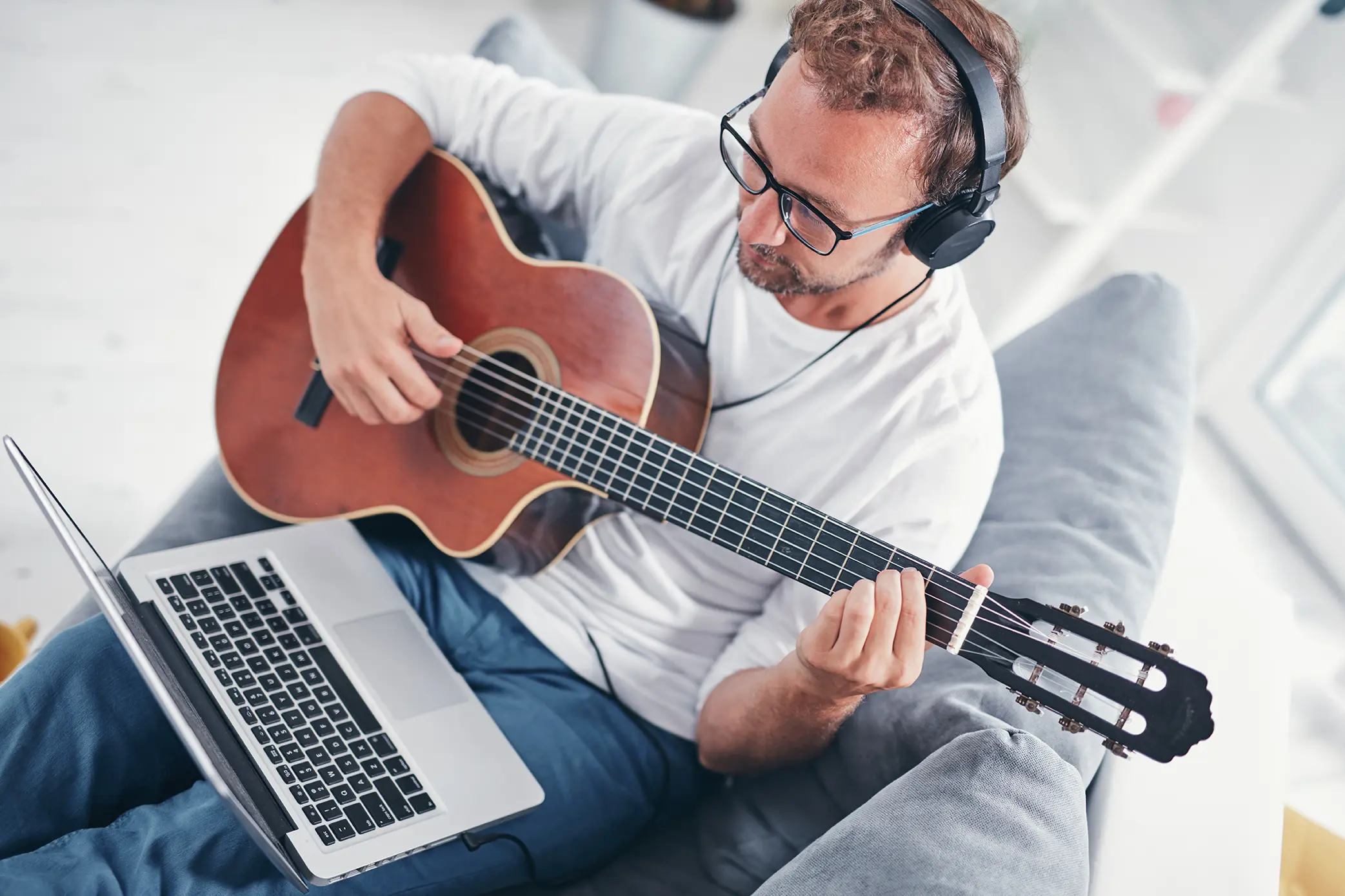 Hombre frente a laptop con una guitarra aprendiendo