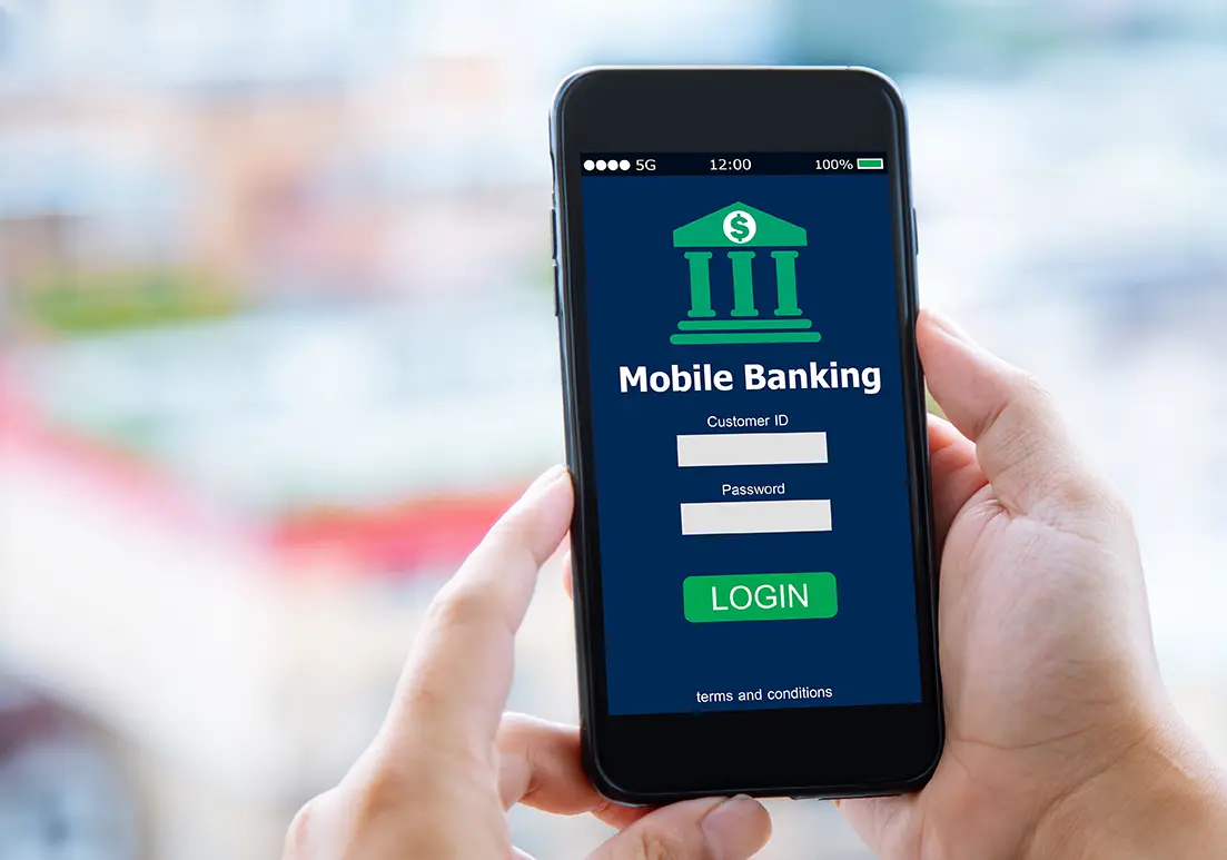 Persona utilizando celular usando la aplicación del banco representando los fraudes bancarios en línea y 7 tips para blindar tu dinero