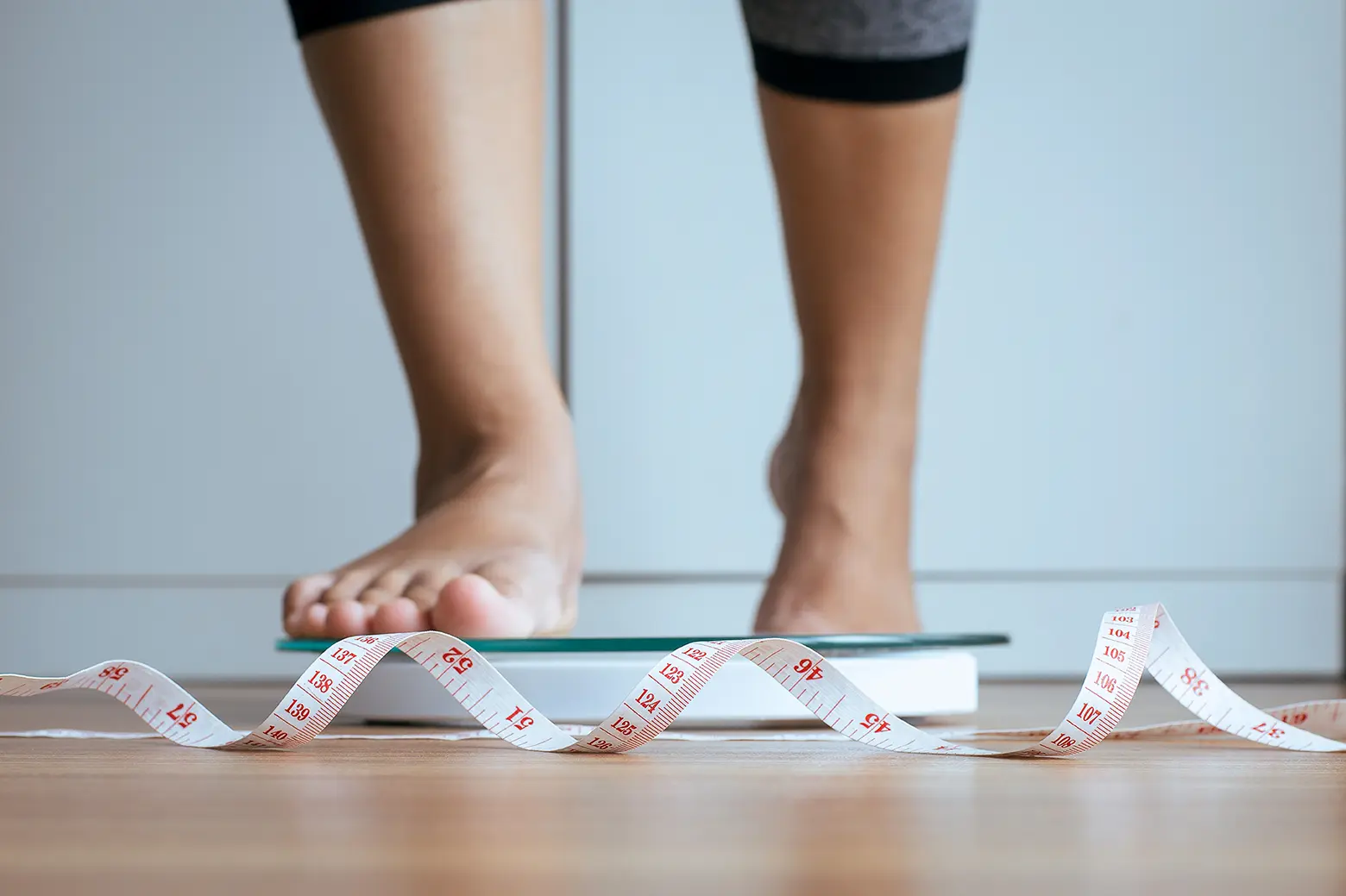 Piernas de persona, subiendo a una báscula con una cinta métrica representando el nuevo escáner corporal que permitirá saber exactamente cuánto peso pierdes y ganas.