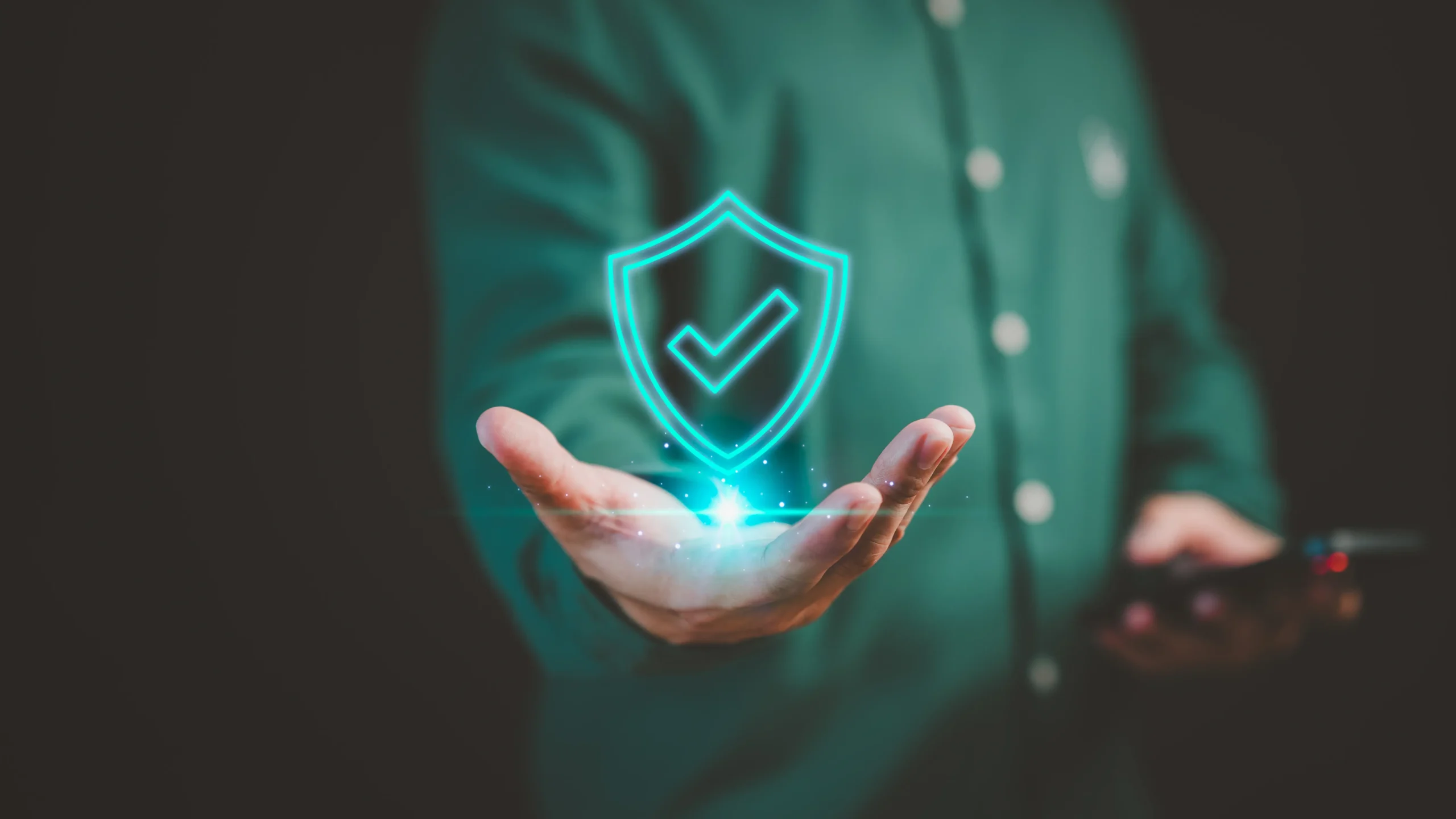 Una persona sostiene un holograma brillante de un escudo con una marca de verificación, simbolizando la ciberresiliencia y la seguridad digital.